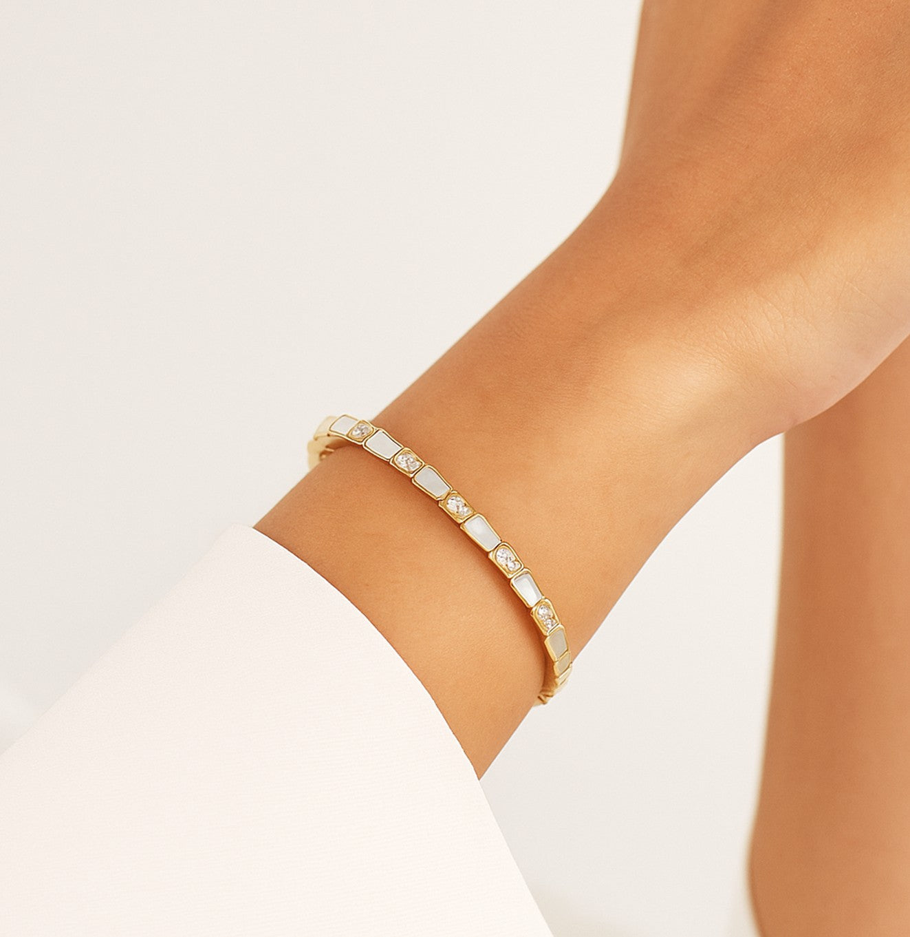 سوار ذهبي مفتوح بلمسات عرق اللؤلؤ وأحجار براقة